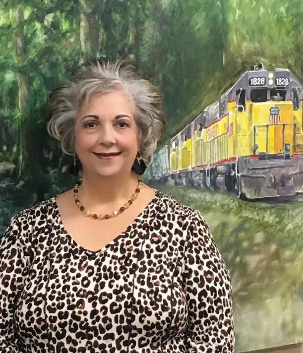 A woman standing in front of a train painting.