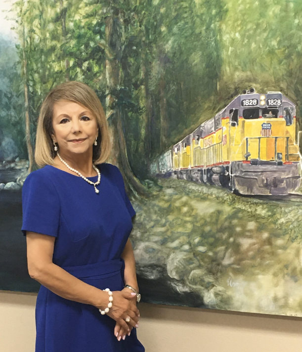 A woman in front of a painting with train on it.