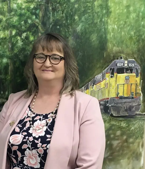 A woman standing in front of a train.