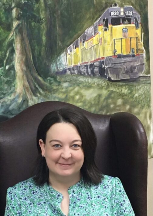A woman sitting in front of a train painting.